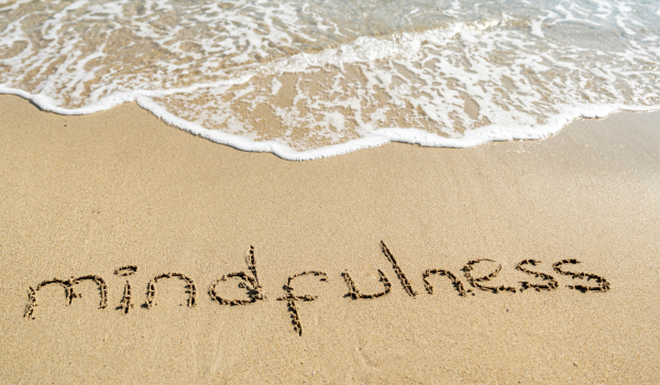 Palavra "mindfulness" escrita na areia da praia