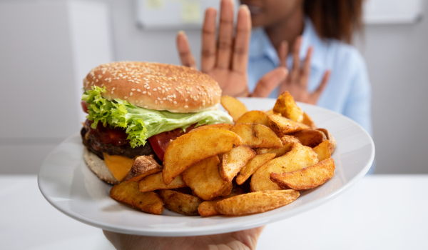 Mulher rejeitando alimento fast food em um prato.
